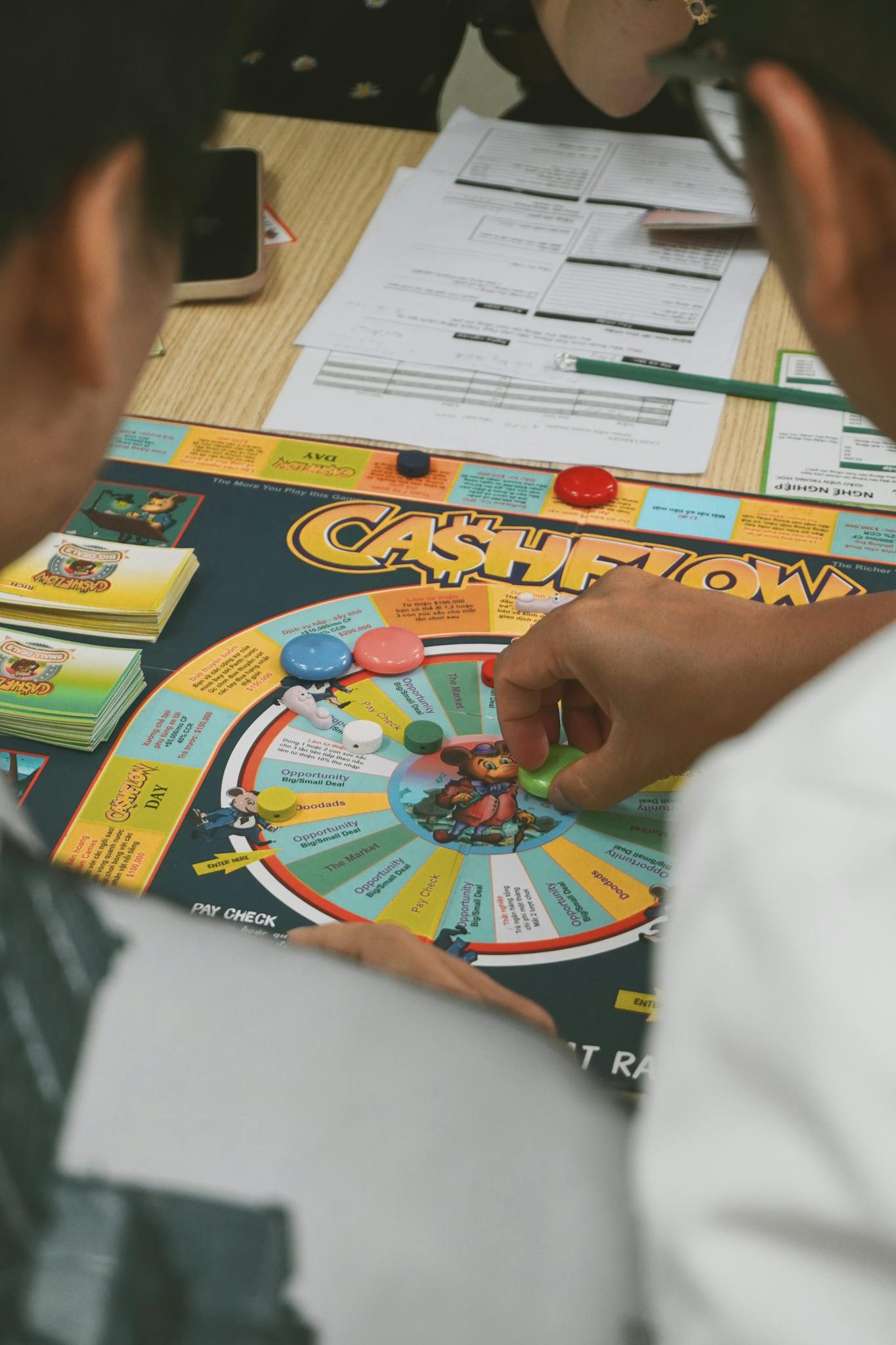 Adults engaged in Cashflow board game session, focusing on financial education and strategy.