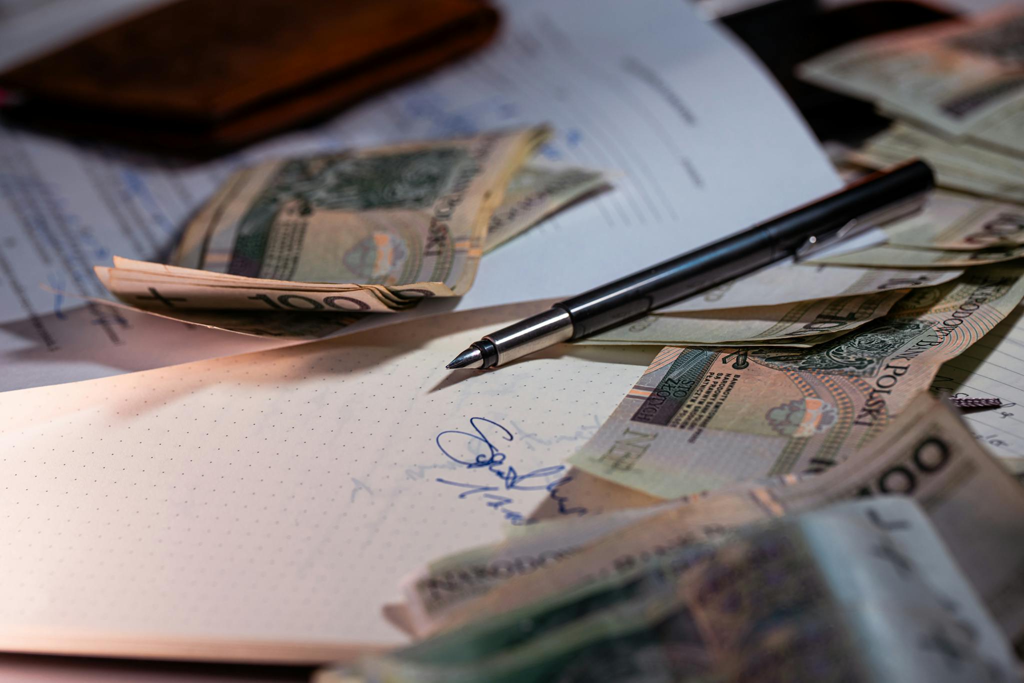 Overhead view of Polish banknotes, documents, and a pen on a desk, highlighting financial planning.